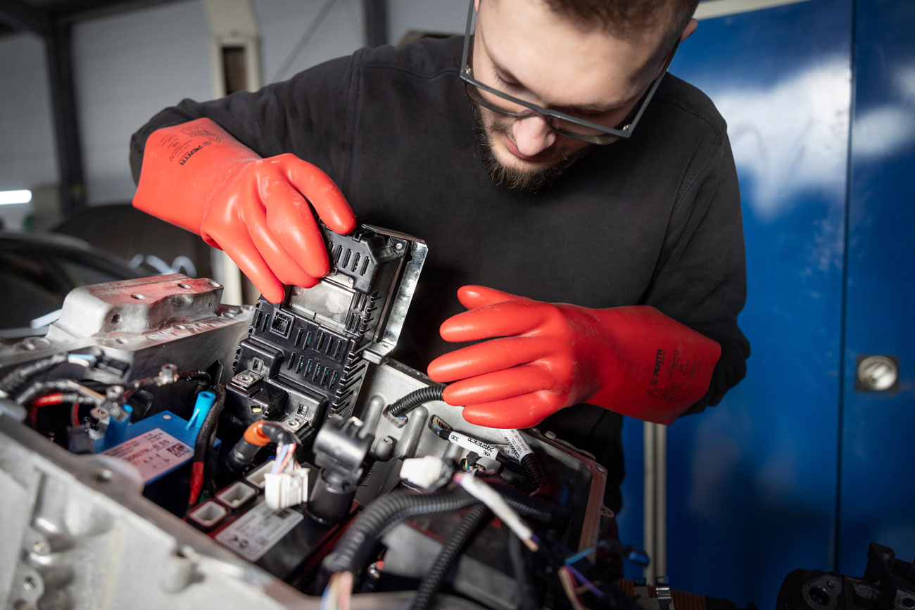 Foto: ein Kfz Mechaniker tauscht Bauteil am Elektromotor aus