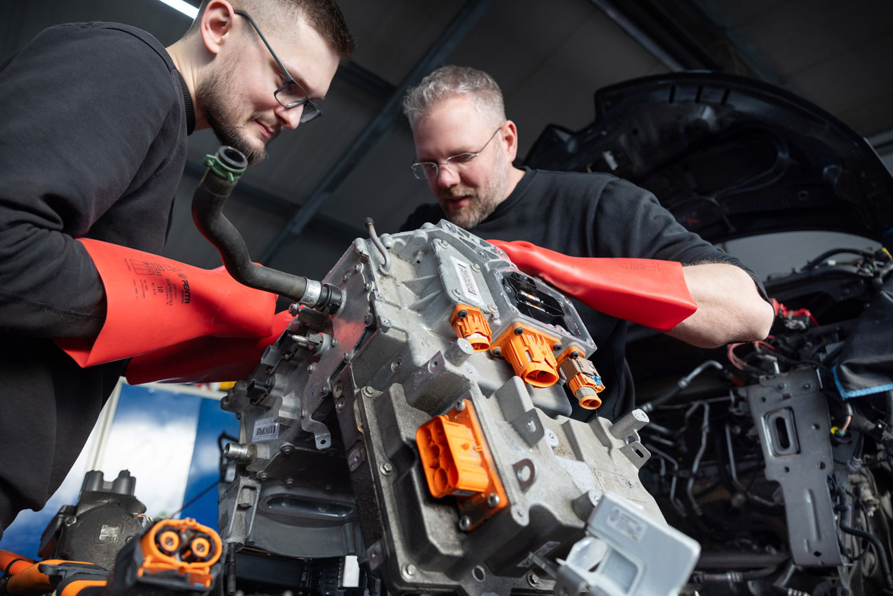 Foto: zwei Kfz Mechaniker reparieren einen Elektromotor